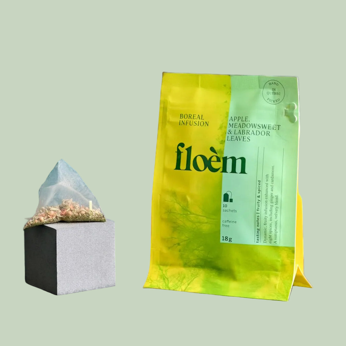 Floem Apple, Meadowsweet & Labrador Leaves boreal herbal tea bag and package with dried botanicals on a sage green background — Sensory for Calm
