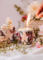 Hand lighting Petit Jardin botanical candle surrounded by fresh pink flowers — candle ritual — Sensory for Calm