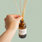 Hand holding Misiyo Rosewood and Amethyst reed diffuser amber bottle — natural scented diffuser — Sensory for Calm